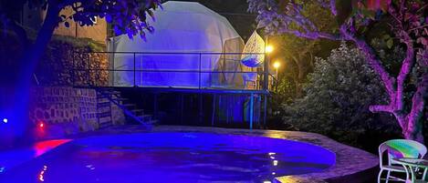 Une piscine dotée d’un espace couvert et d’une chaise.