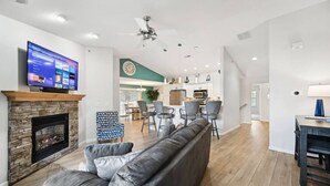 A spacious living room with a stone fireplace, a grey sofa, and a flat-screen TV mounted on the wall. - Vacation Awaits at Delton Grand (Wisconsin Dells)