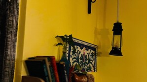 Une étagère avec des livres et une plante en pot, le tout adossé à un mur jaune.