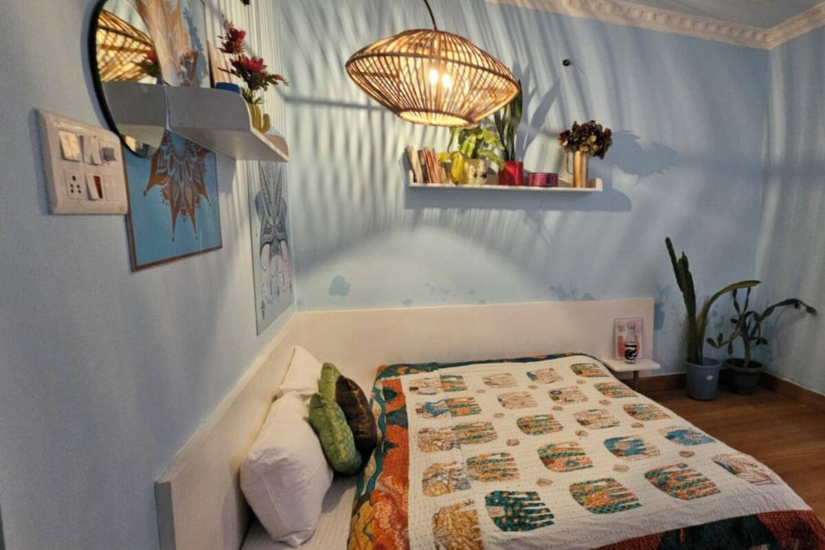 Un dormitorio con cama, mesita de noche, lámpara colgante y planta en maceta.