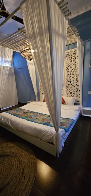 A bedroom with a canopy bed, a decorative wall panel, and a blue accent wall.