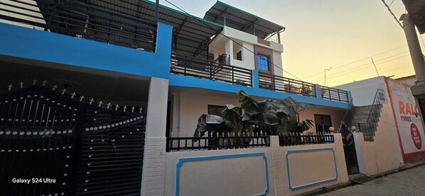 A two-story building with a blue and white facade, a gated entrance, and a sign for 'RAC Tyres'.