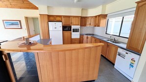 A kitchen with wooden cabinets, a refrigerator, an oven, a sink, and a window.