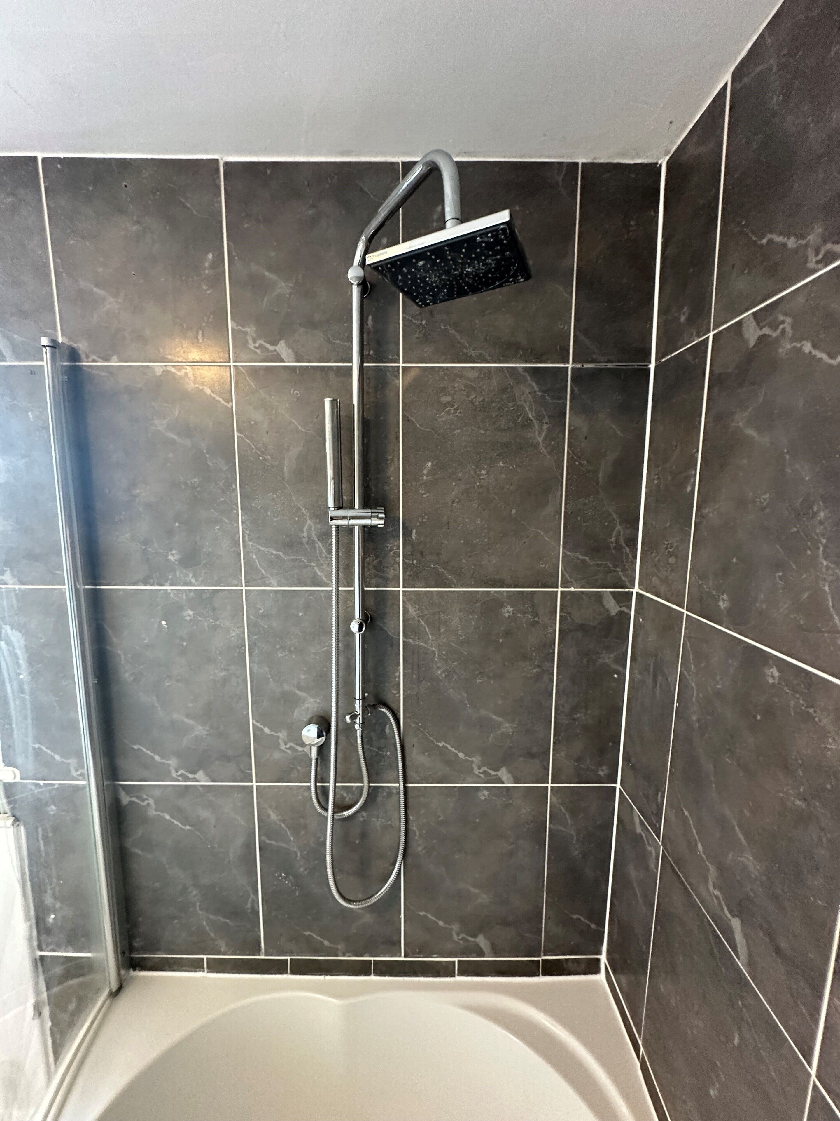 A shower area with a handheld showerhead and a wall-mounted showerhead.