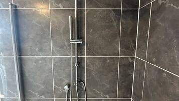 A shower area with a handheld showerhead and a wall-mounted showerhead.