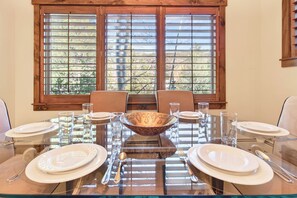A dining table set for four with a central decorative bowl, surrounded by chairs and glassware.