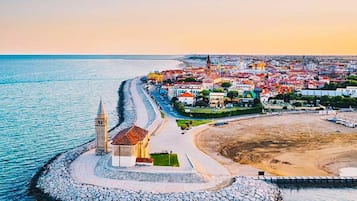 Un pueblo costero con una iglesia destacada, una playa y un espigón rocoso.