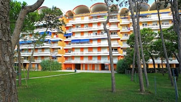 Un hotel de varios pisos con balcones, un patio con césped y árboles.