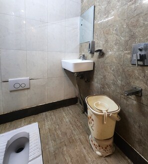 A bathroom with a toilet, sink, and hand dryer. - Hotel Sonic Palace  (New Delhi)
