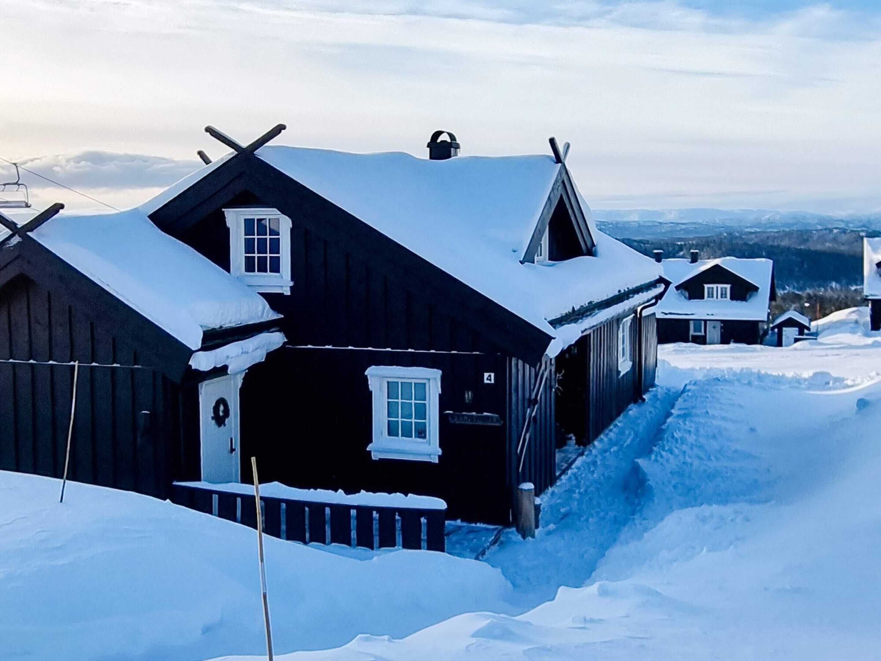 A wooden cabin with a steep roof, surrounded by snow.