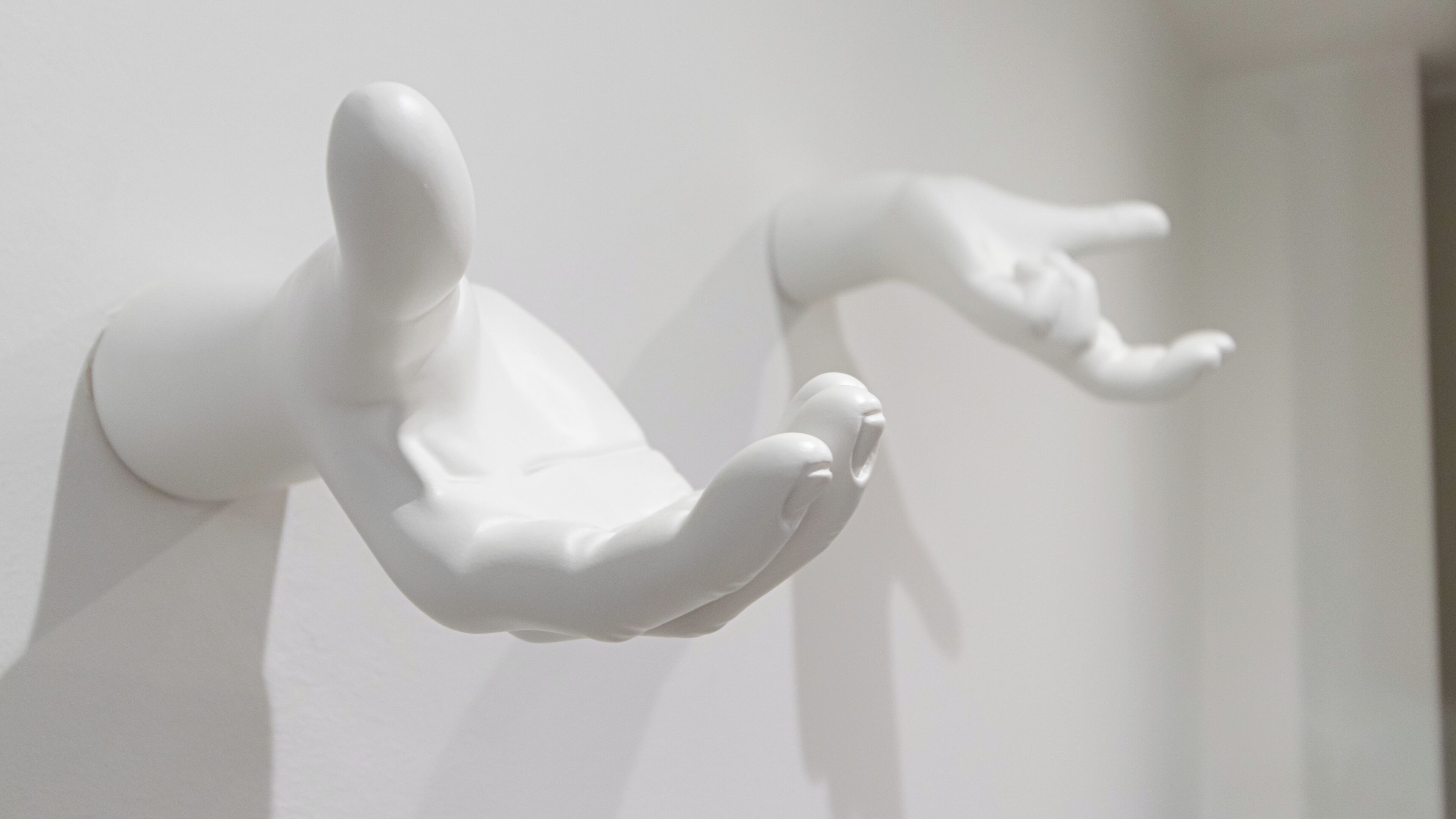 A white sculpture of a human figure in a dynamic pose, mounted on a wall.
