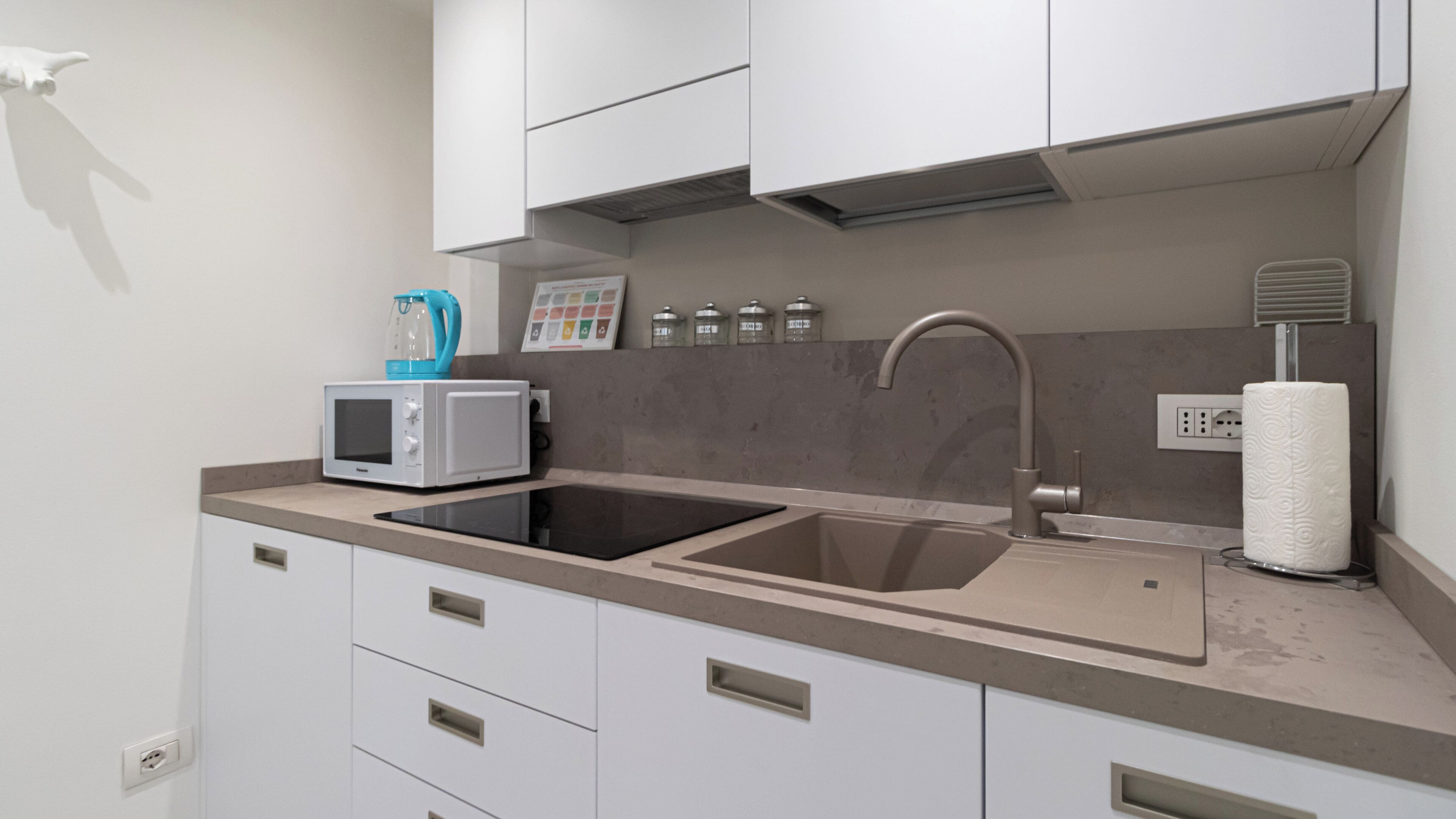 A modern kitchen with two sinks, a microwave, and a kettle.