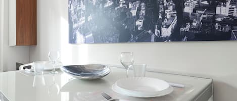 A dining table with a white plate, two wine glasses, and a clear glass.