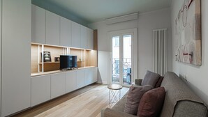 Ein modernes Wohnzimmer mit einer Couch, einem Fernseher auf einem Schrank und einem kleinen Tisch.