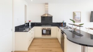 Eine moderne Küche mit schwarzem Arbeitsplatz, Edelstahlgeräten und Holzboden.
