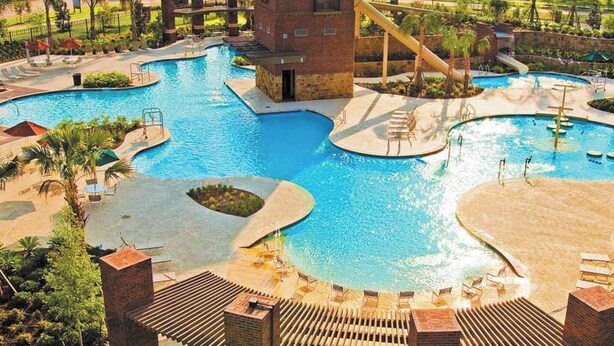 A large outdoor swimming pool with multiple sections and a central tower structure. - Relax in Style at Our Missouri City Getaway (Missouri City)
