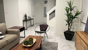 A modern living room with a sofa, coffee table, and a potted plant. - Relax in Style at Our Missouri City Getaway (Missouri City)
