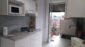 A compact kitchen with a gas stove, a microwave, and a small sink. - Bibbi's House San Lorenzo (Rome)