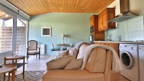 A cozy living room with a sofa, a dining table, and chairs. There is a washing machine in the corner. - Apartment with private garden and modern amenities (Groix)