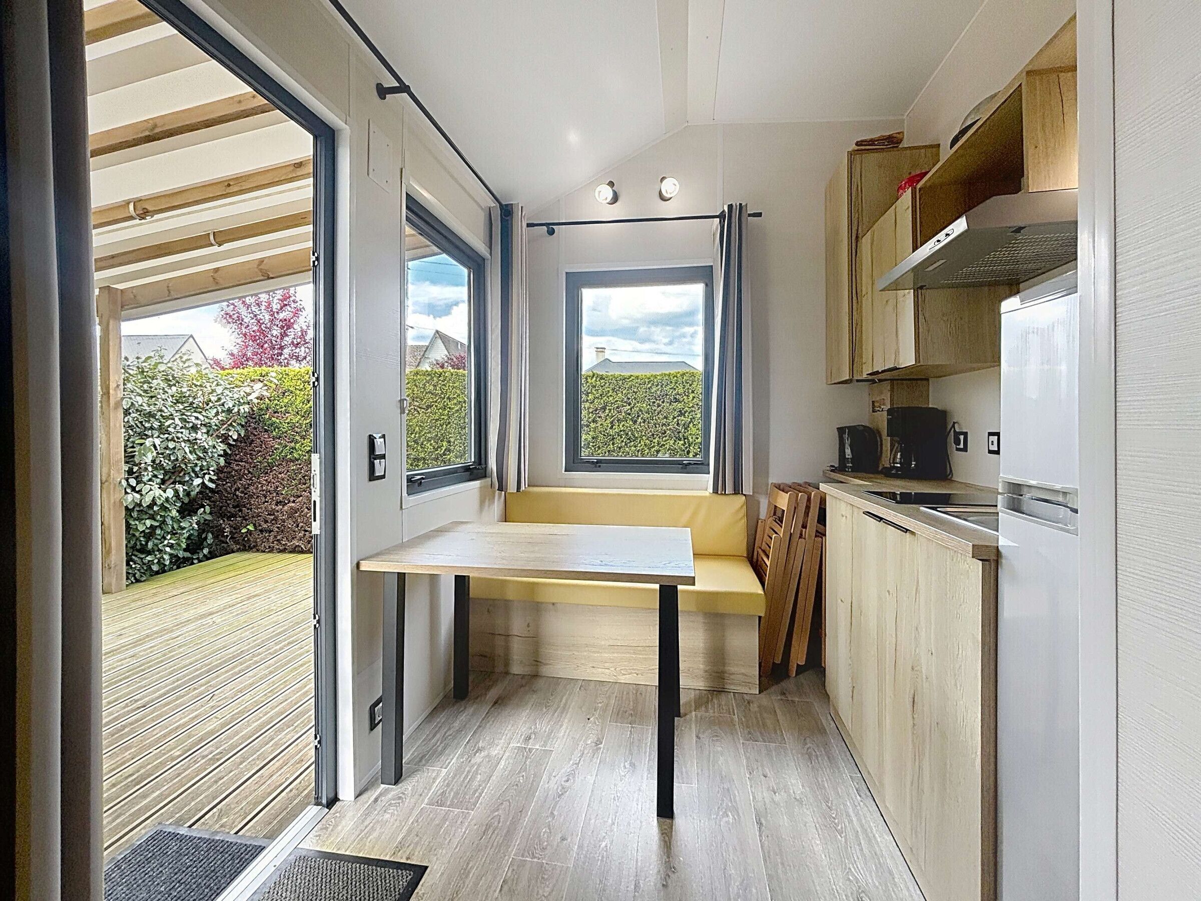 Eine kleine Küche mit integriertem Sitzplatz, einem Fenster und Blick auf den Garten.
