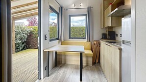 Une cuisine compacte avec un banc intégré, une fenêtre et une vue sur le jardin.