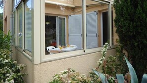 Ein Zimmer mit großem Fenster, einer Schiebetür und Blick auf einen Balkon mit Gartenmöbeln.