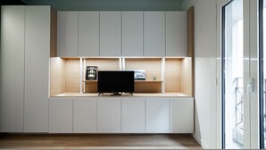 Una sala moderna con estanterías empotradas, un televisor de pantalla plana y un ventanal que da a un balcón.