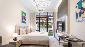 A modern hotel room with a large bed, a desk with dining set, a TV, and artwork on the walls. - Sleek Studio Apartment in Azizi Riviera- Suiteable (Dubai)
