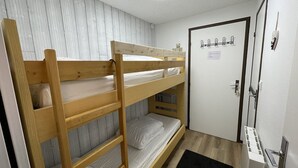 A bunk bed room with a wooden bunk bed, a white door with a keyhole, and a small black rug on the floor. - Studio in resort, at the foot of slopes, Southeast balcony (Le Lioran)