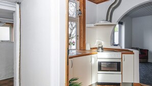 A compact kitchen with white cabinets, a stove, and a sink. - Apartment in Ringkobing With Garden (Ringkobing)