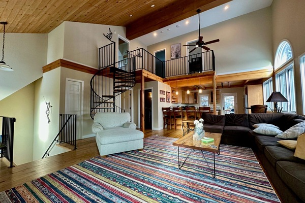 Living area with cozy seating, a stylish rug and a spiral staircase.