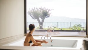 Una persona en una bañera con vista a un árbol y una valla.