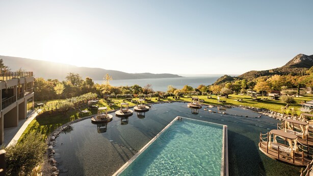 Una piscina con sillones de descanso, vistas al mar y un paisaje montañoso.
