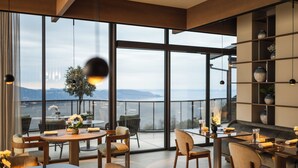 Un comedor moderno con ventanas amplias, mobiliario de madera y vistas a la ciudad.