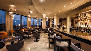 Un área de bar moderna con asientos, una barra y vistas a la ciudad.
