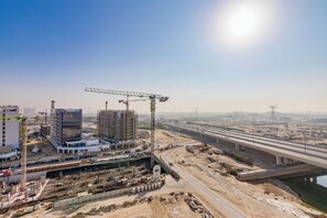 A construction site with cranes, buildings, and a highway overpass. - GLOBALSTAY. Azizi Riviera 48 (Dubai)