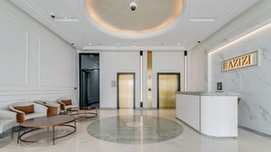 En moderne lobby med receptionsdisk, to elevatorer og siddeområde.