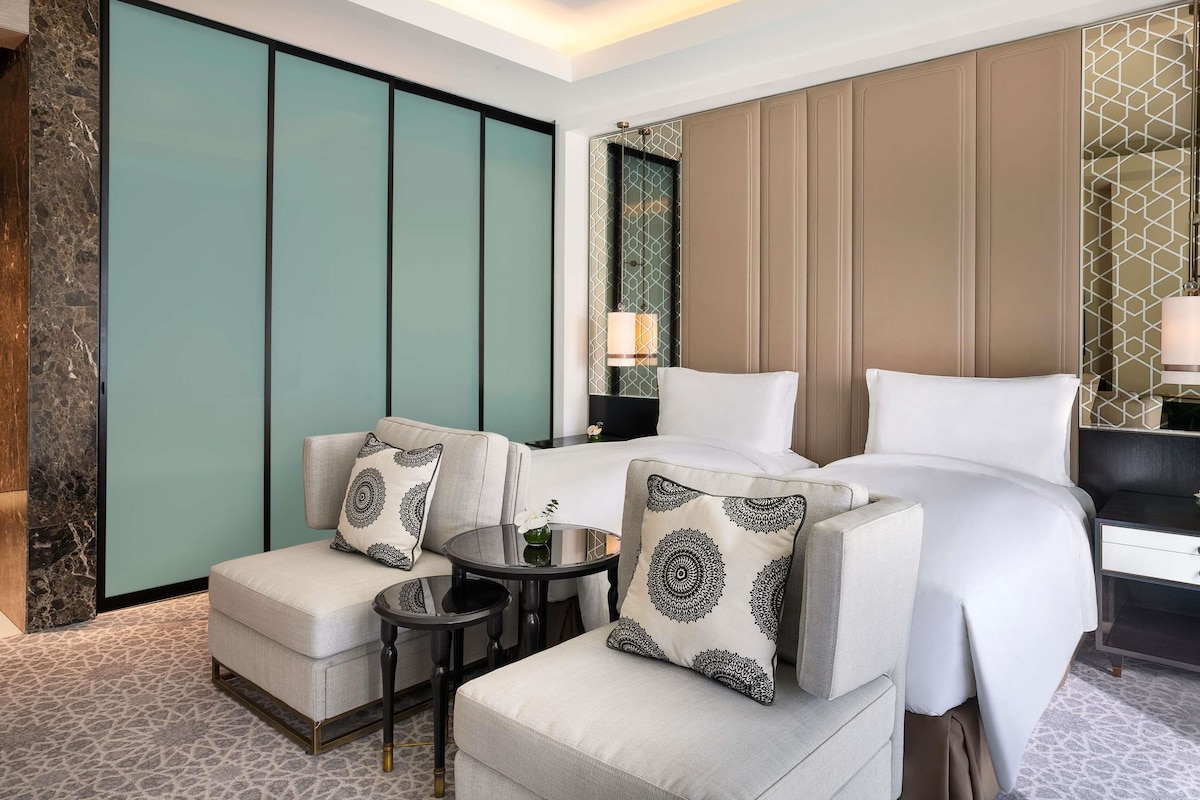 A hotel room with a bed, two armchairs, a small table, and a nightstand.