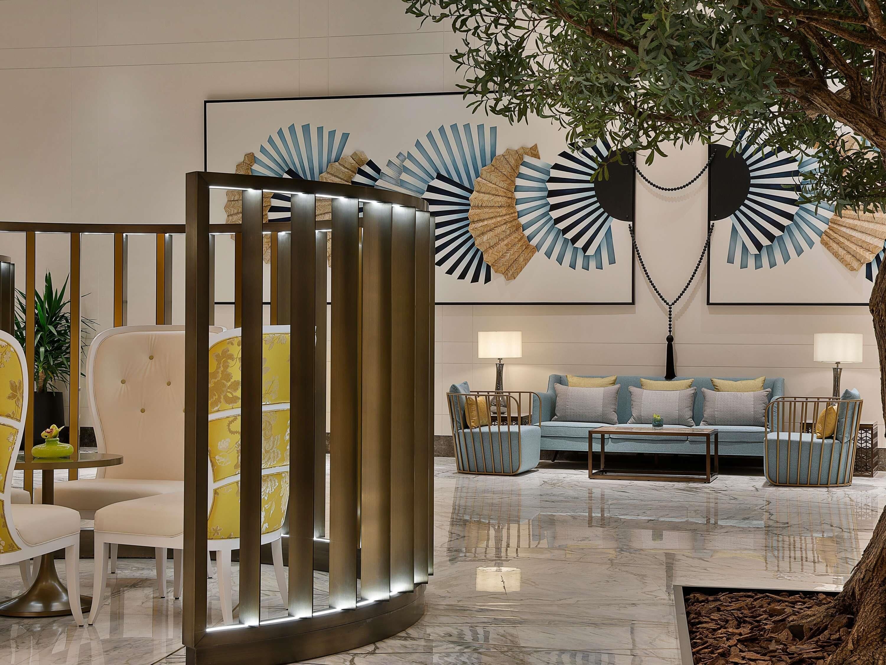 A modern lobby with a seating area, a decorative tree, and wall art.