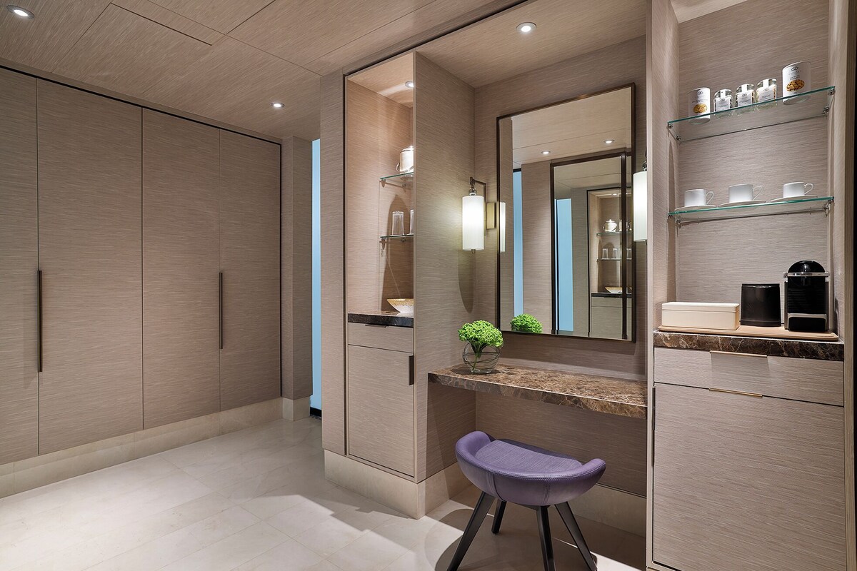 A modern bathroom with a vanity, mirror, and shelves with toiletries.