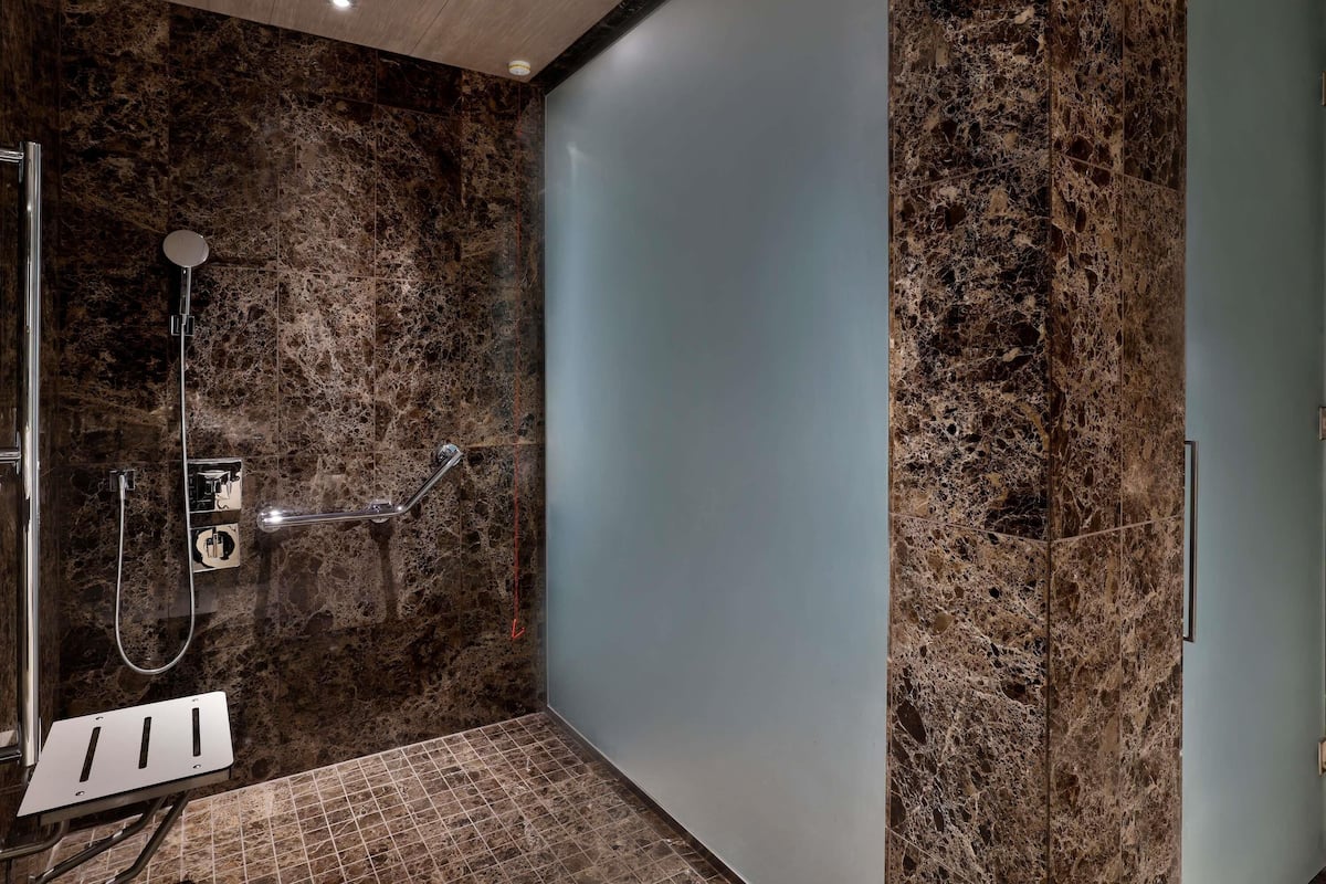 A modern bathroom with a shower, marble walls, and a glass partition.