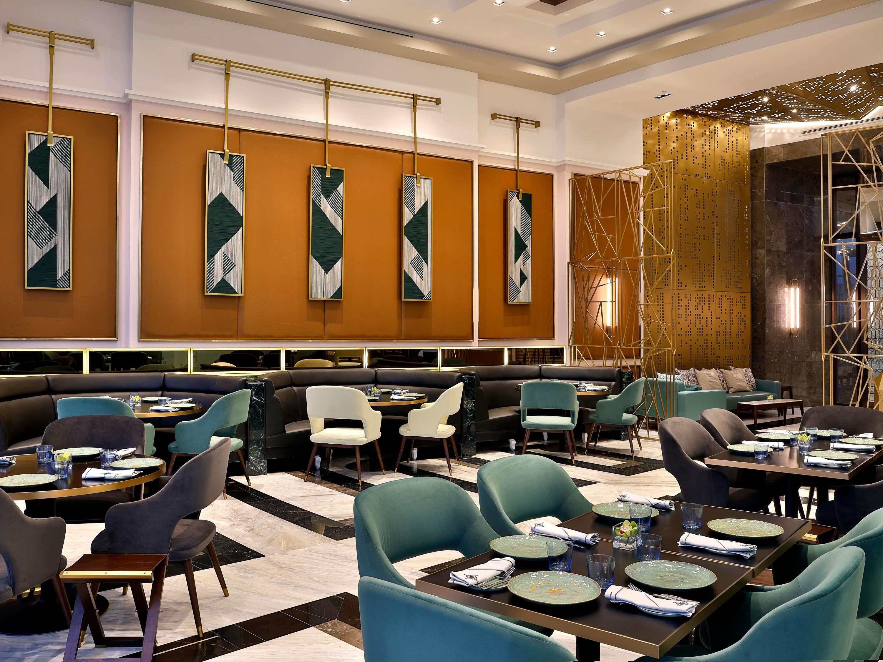 A modern restaurant interior with high tables, cushioned seating, and geometric wall art.
