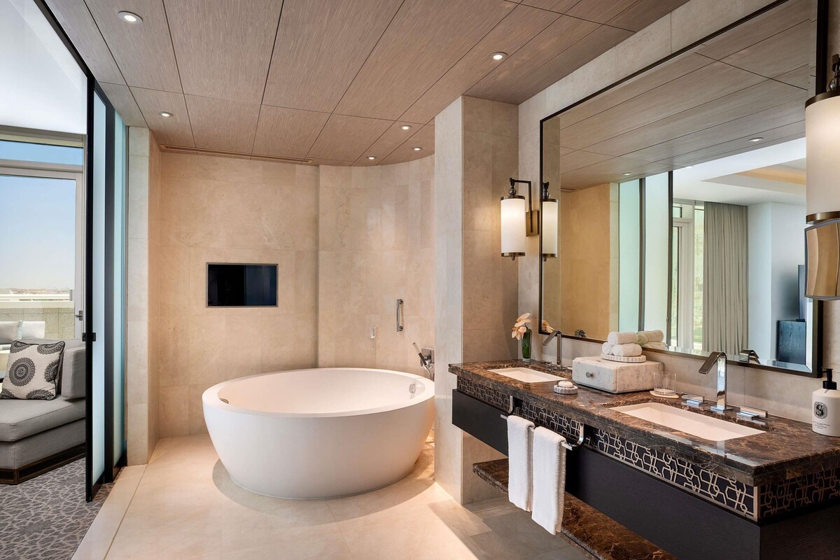 A modern bathroom with a freestanding bathtub, a large mirror, and a vanity with a marble countertop.