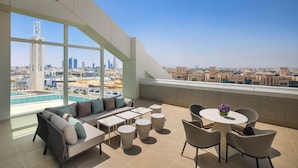 A rooftop terrace with a city view, a pool, and outdoor seating.