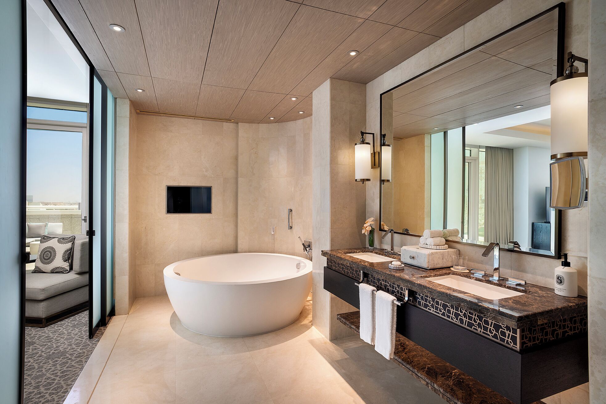 A modern bathroom with a freestanding bathtub, a large mirror, and a marble countertop.