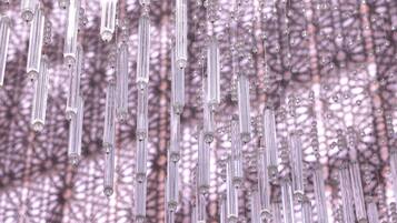 A series of vertical hanging structures with clear tubes and spherical elements, set against a patterned background.