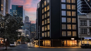 Un bâtiment moderne, facilement reconnaissable à son grand panneau « TRIBE », doté d’une façade en verre et de nombreuses fenêtres.