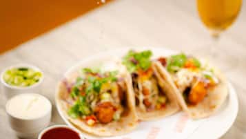 A plate of tacos with condiments and a glass of wine on a table.
