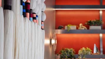 A room with a white curtain, a red wall, and a shelf with plants and a small decorative item.