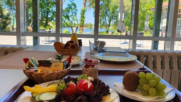 Une table dressée avec de la nourriture et des boissons, un panier en osier contenant du fromage, une assiette de charcuterie et une assiette de raisins.